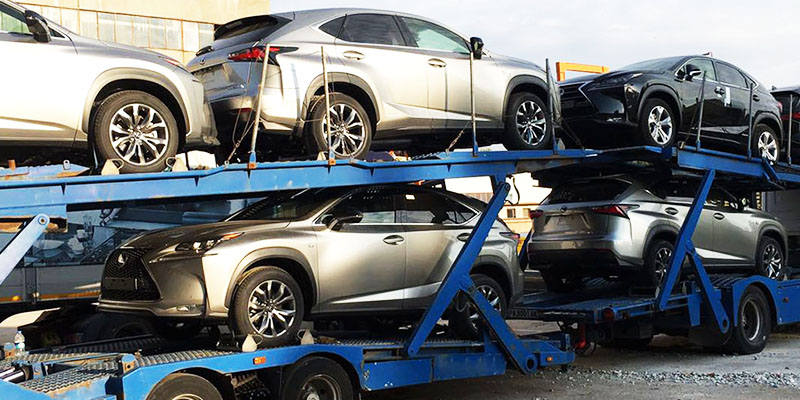 grupo de autos averiados siendo transportados sin rodar en madrina nodriza color azul