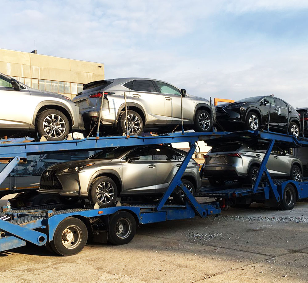 grupo de autos averiados siendo transportados sin rodar en madrina nodriza color azul